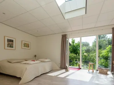 a bedroom with a bed and a large window at Holiday Home in Bergen near Bergerbos Forest in Bergen