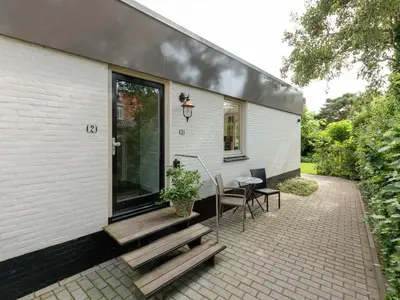 a house with a patio with a table and chairs at Holiday Home in Bergen near Bergerbos Forest in Bergen