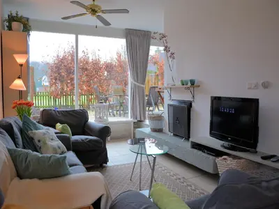 a living room with couches and a flat screen tv at Holiday Home Noordwijk near the Beach in Noordwijkerhout