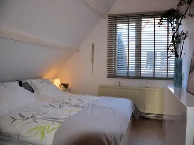 a bedroom with a white bed and a window at Holiday Home Noordwijk near the Beach in Noordwijkerhout