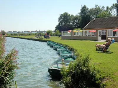 a row of green boats in a river at Holiday Home Noordwijk near the Beach in Noordwijkerhout