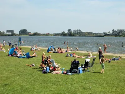 a group of people sitting on the grass by the water at Holiday Home Noordwijk near the Beach in Noordwijkerhout