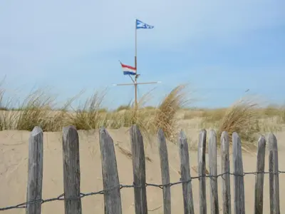 a wooden fence in front of a sandy beach at Holiday Home Noordwijk near the Beach in Noordwijkerhout