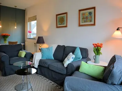 a living room with two blue couches and a table at Holiday Home Noordwijk near the Beach in Noordwijkerhout