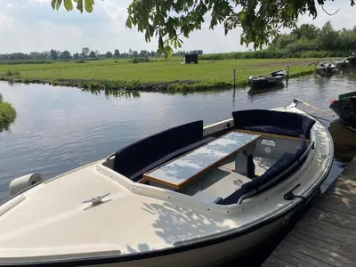 a white boat sitting on the water next to a dock at Cottage in Edam near IJsselmeer Lake in Edam