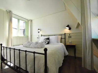 a bedroom with a bed with white sheets and a window at Cottage in Edam near IJsselmeer Lake in Edam