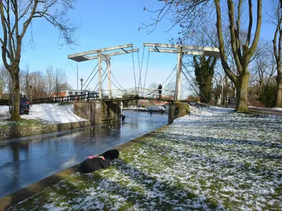 a child sitting on the snow next to a river at Cottage in Edam near IJsselmeer Lake in Edam