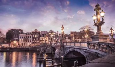 a bridge over a river with buildings and a city at The Hendrick's Hotel in Amsterdam