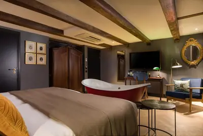 a bedroom with a bed and a chair and a television at The Hendrick's Hotel in Amsterdam