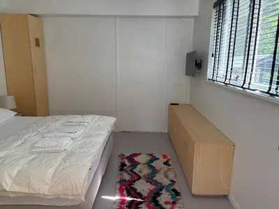 a bedroom with a bed and a rug and a window at Duinappartementen Schoorl in Schoorl