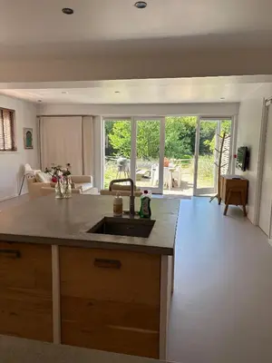 a kitchen with a sink and a living room at Duinappartementen Schoorl in Schoorl