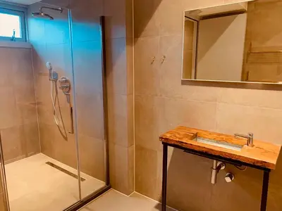 a bathroom with a shower and a sink and a mirror at Duinappartementen Schoorl in Schoorl
