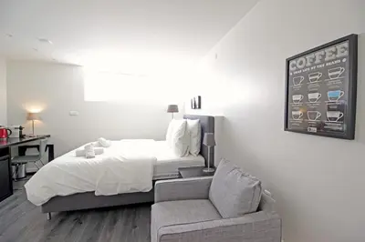 a white bedroom with a bed and a couch at Guesthouse Prinsencanal 2 in Amsterdam