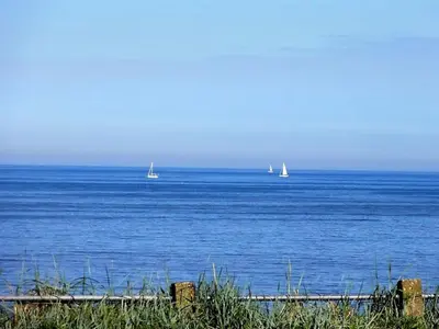 two boats in the ocean with sailboats in the distance at Benny's Beach House 1 in Zandvoort