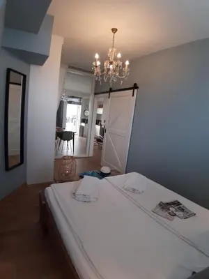 a bedroom with a white bed and a chandelier at Benny's Beach House 1 in Zandvoort