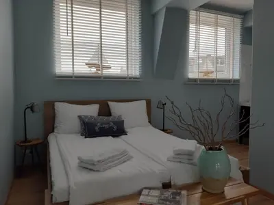 a bedroom with a white bed with two windows at Benny's Beach House 1 in Zandvoort