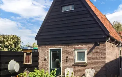 a small brick house with a black roof at De Bedstee in Opperdoes