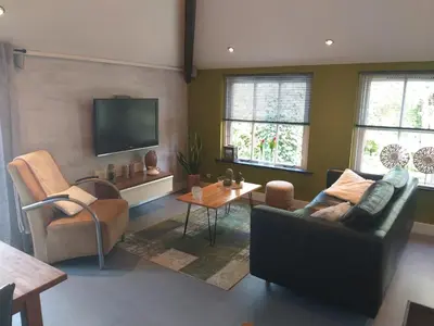 a living room with a couch and chairs and a flat screen tv at Holiday Home Canal View in Alkmaar