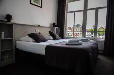 a hotel room with a bed and a large window at Hotel de Gaaper in Amersfoort
