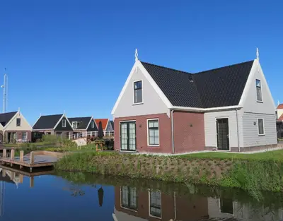 a house with a black roof next to a river at Luxurious Water Villa in Uitdam