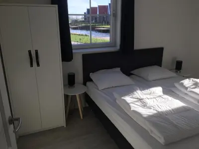 a bed with white sheets and pillows and a window at Luxurious Water Villa in Uitdam