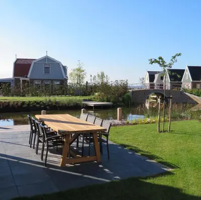 a wooden table and chairs in a yard at Luxurious Water Villa in Uitdam