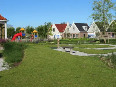 a park with a playground and a bench in the grass at Luxurious Water Villa in Uitdam