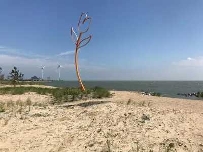 a sculpture on a beach with wind turbines in the background at Luxurious Water Villa in Uitdam