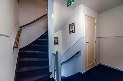 a staircase in a house with blue carpeting and a door at Pension Sixtysix in Zandvoort