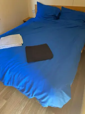 a blue bed with a black blanket and a book on it at Chalet Jade in IJmuiden