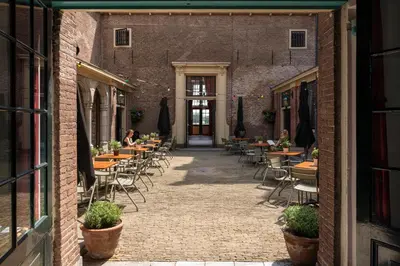 a courtyard with tables and chairs in a building at Stayokay Hostel Heemskerk - fully renovated April 2026 in Heemskerk