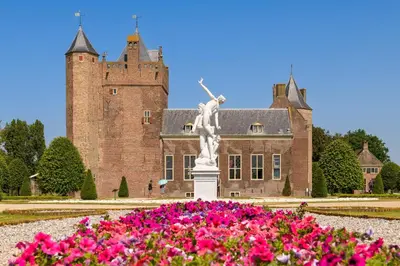 a statue in front of a castle with pink flowers at Stayokay Hostel Heemskerk - fully renovated April 2026 in Heemskerk
