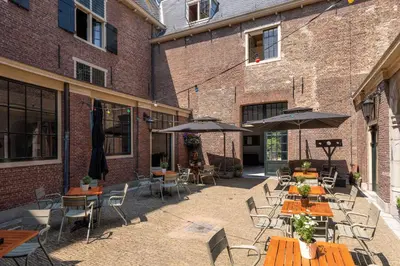 an outdoor patio with tables and chairs and umbrellas at Stayokay Hostel Heemskerk - fully renovated April 2026 in Heemskerk