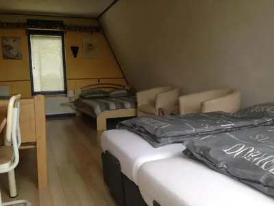a room with two beds and a table and chairs at B&B-Edam in Edam
