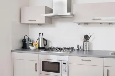 a white kitchen with a stove and a microwave at NEW Appartment Zandvoort! in Zandvoort