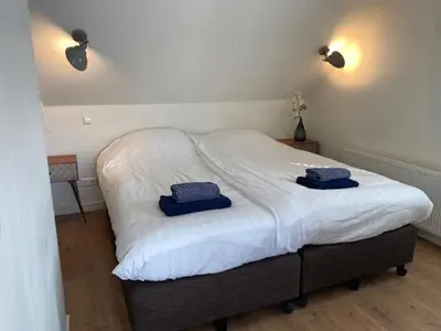 a bedroom with a bed with two blue pillows on it at NEW Appartment Zandvoort! in Zandvoort