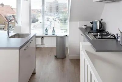 a white kitchen with a sink and a counter at NEW Appartment Zandvoort! in Zandvoort