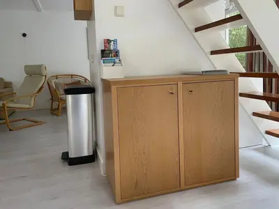 a small wooden cabinet in a room with stairs at The Beach House in Noordwijkerhout