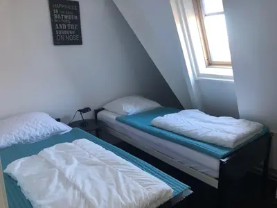 two beds in a small room with a window at Appartement Modern Egmond in Egmond aan Zee