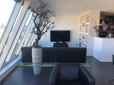 a living room with a couch and a tv and some plants at Appartement Modern Egmond in Egmond aan Zee