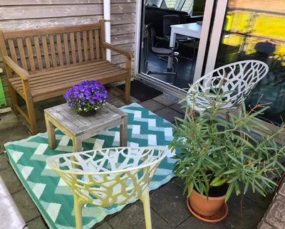 a porch with a bench and a table and flowers at Appartement Modern Egmond in Egmond aan Zee