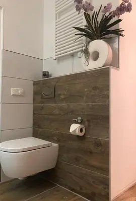 a bathroom with a toilet and a plant on a wall at Appartement Modern Egmond in Egmond aan Zee