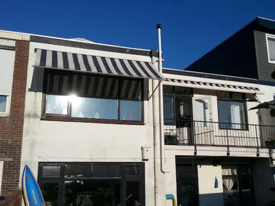 a white house with a black and white awning at Kampan in Zandvoort