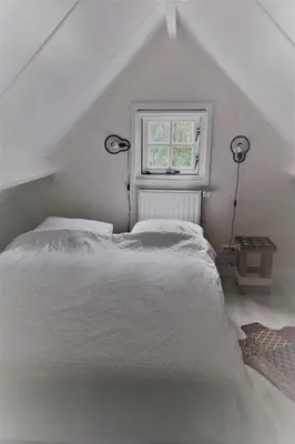 a bedroom with a white bed and a window at Gina's garden house in Amsterdam