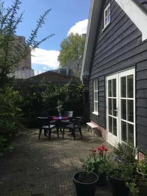 a patio with a table and chairs next to a house at Gina's garden house in Amsterdam