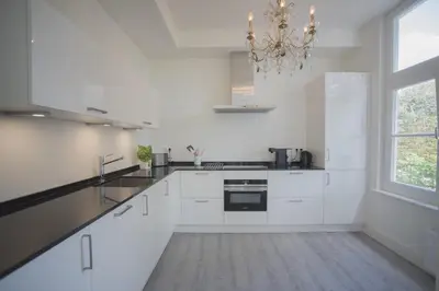 a kitchen with white cabinets and a chandelier at Luxury Upstairs & Downstairs Apartments in Zandvoort