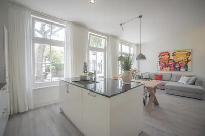 a white kitchen with a island in a living room at Luxury Upstairs & Downstairs Apartments in Zandvoort