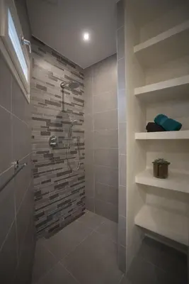 a bathroom with a shower with a stone wall at Luxury Upstairs & Downstairs Apartments in Zandvoort