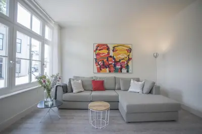 a living room with a couch and a painting on the wall at Luxury Upstairs & Downstairs Apartments in Zandvoort