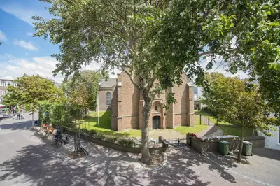 a building with a tree and benches in front of it at Luxury Upstairs & Downstairs Apartments in Zandvoort